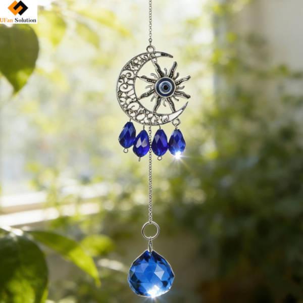 Blue Suncatcher Eyes moon crystal pendant with sun and eye design, featuring blue teardrop crystals and a large faceted blue crystal, perfect for catching light in home decor.