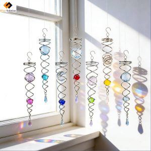 Colorful Faceted Crystal Ball Twisters hanging by a sunlit window, casting rainbow prisms. B2B outdoor garden & home decor wind spinners.